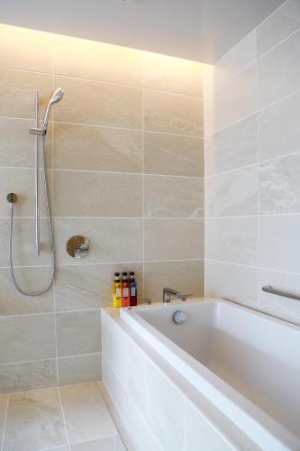 a white bathroom with a tub and a shower at Hotel Comfact in Tokyo