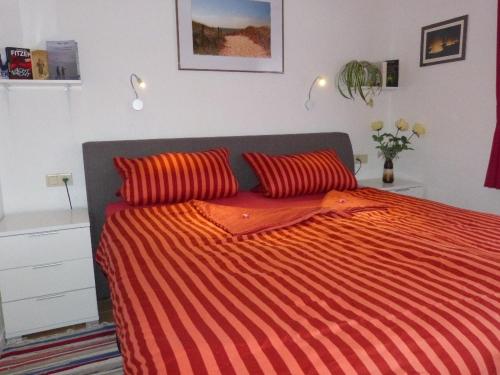 a bedroom with a bed with an orange striped comforter at Fewo-Nordseestrand in Büsum