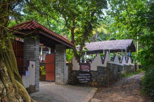 a building with a sign next to a tree at Goyambokka Guesthouse in Tangalle