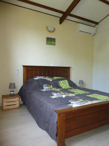 1 dormitorio con 1 cama grande y cabecero de madera en Chez Solange et Michel, en Sainte-Rose