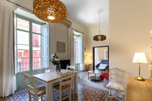 a dining room with a table and chairs and a living room at Teatro Suites Málaga in Málaga