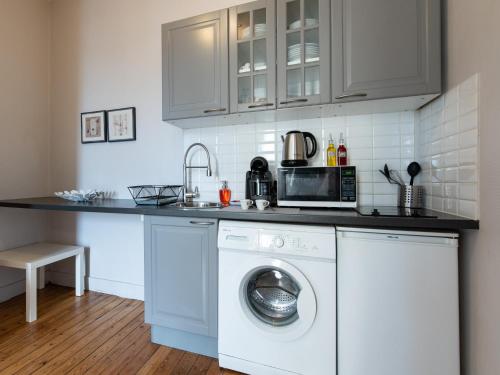 une cuisine avec un lave-linge et un micro-ondes dans l'établissement Le Nid Lyonnais - Le Vienne, à Lyon