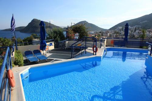 a swimming pool with chairs and a view of the water at Heliotopos Apartments in Tolo