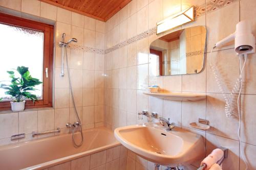 a bathroom with a sink and a tub and a mirror at Gasthof Zum Lendwirt in Westendorf