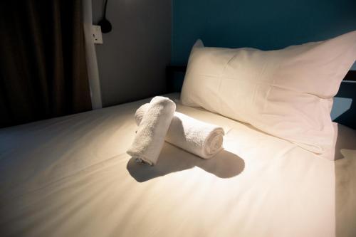a pair of towels on a bed with a pillow at Vibrant Hostel in Kota Kinabalu