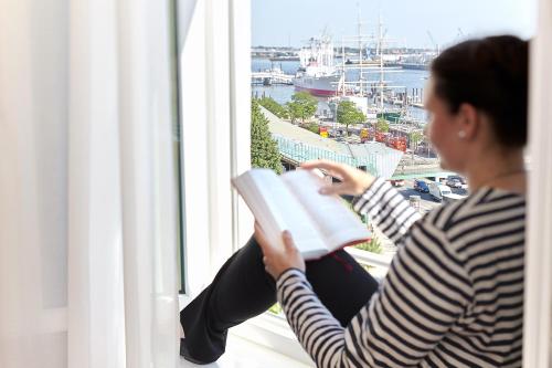 a woman is reading a book while sitting on a balcony at Hotel Hafen Hamburg in Hamburg