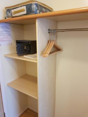 a closet with a book shelf with a microwave at Travel Plaza Hotel in Desborough