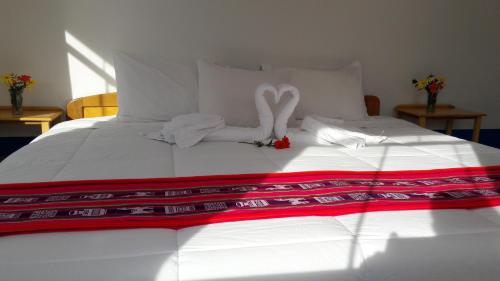 a white bed with two swans made out of towels at Amantani Lodge in Amantani