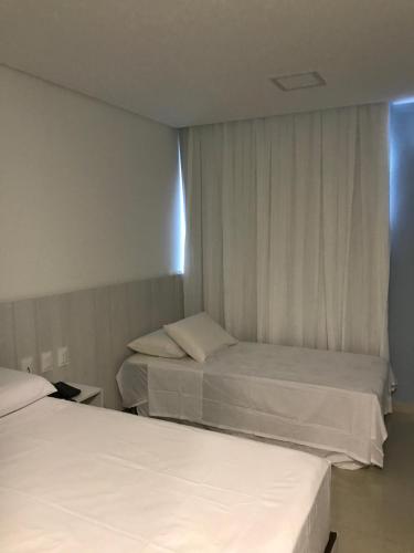 um quarto de hotel com duas camas e uma janela em APART HOTEL MARINAS TAMANDARÉ - Flat 104 em Tamandaré