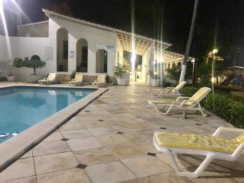 a swimming pool with lounge chairs next to a house at APART HOTEL MARINAS TAMANDARÉ - Flat 104 in Tamandaré