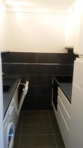 - une cuisine avec du carrelage noir et un lave-linge/sèche-linge dans l'établissement Ski Soleil 108, à Manigod