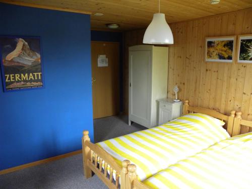 a bedroom with two beds and a blue wall at Hotel Restaurant Walliser Sonne in Reckingen - Gluringen