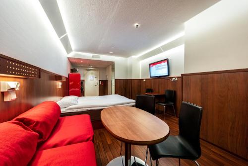um quarto de hotel com um sofá vermelho e uma mesa em Omena Hotel Jyväskylä em Jyväskylä
