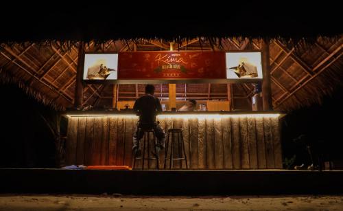 a man standing at a bar at night at Kimo Resort Pulau Banyak Aceh Singkil in Alaban
