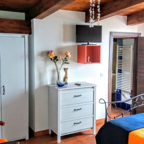 a bedroom with a dresser with a vase of flowers on it at B&B Le Anthos in Marina di Camerota