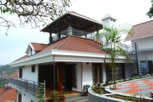 a house with a balcony on top of it at Zenha Resorts in Munnar