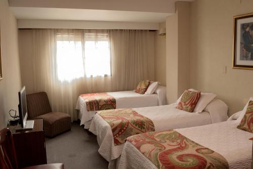 a hotel room with three beds and a window at Hotel Centro in Santiago del Estero