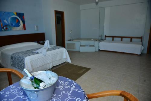 a room with a bed and a table with a bowl at De Rose Praia Hotel in Torres
