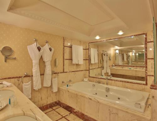 a bathroom with a tub and a large mirror at Regency Palace Amman in Amman