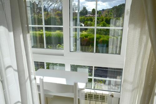 a room with a white chair and two windows at Hotel Alda Santa Cristina in Perillo