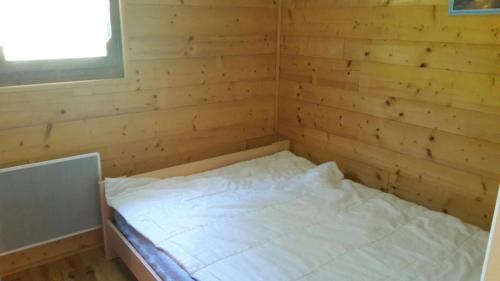 uma cama num quarto com uma parede de madeira em MONT BLANC Soleil C-4 em Manigod