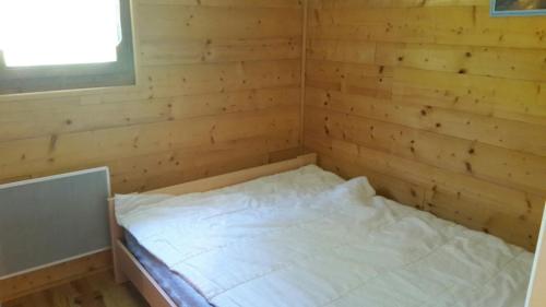 un lit dans une chambre avec un mur en bois dans l'établissement MONT BLANC Soleil C-4, à Manigod