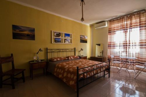 a bedroom with a bed and a chair and a window at B&B la Bitta in Cagliari