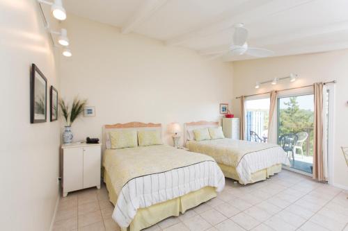 a white bedroom with two beds and a balcony at Driftwood Resort on the Ocean in Montauk
