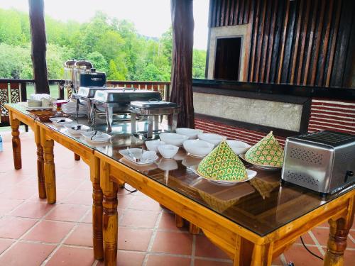 einem Holztisch mit Schalen und Geschirr darauf in der Unterkunft Bussarin Mansion in Ko Yao Yai