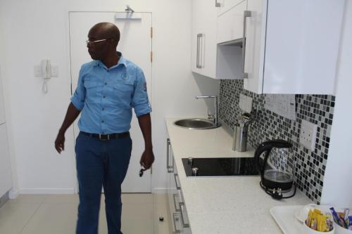 a man standing in a kitchen next to a sink at Pat Luxurious Studio in Gaborone