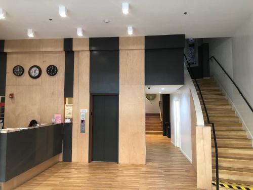 a hallway with a staircase and a clock on the wall at Orange Village Hostel in San Francisco
