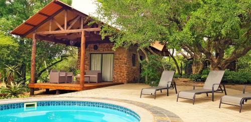 a swimming pool with chairs and a pavilion at Belvedere Game Ranch in Magudu