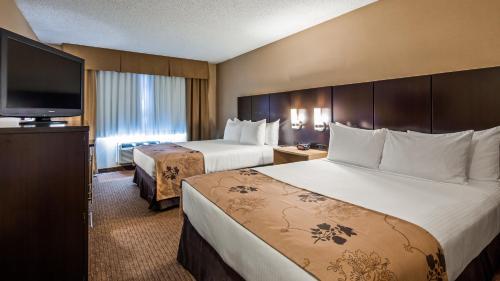 a hotel room with two beds and a flat screen tv at Best Western Seattle Airport Hotel in SeaTac