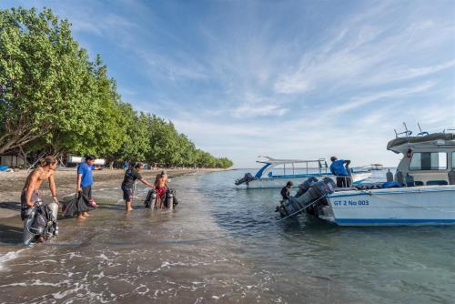 a group of people getting on a boat in the water at Hotel Pondok Sari Beach & SPA Resort in Pemuteran