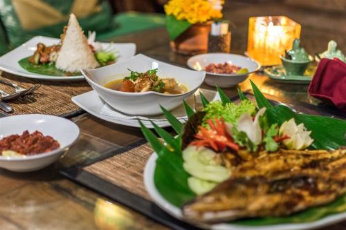 a table with plates of food and bowls of food at Hotel Pondok Sari Beach & SPA Resort in Pemuteran