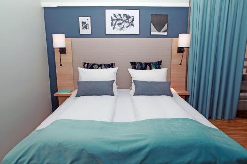 1 dormitorio con 1 cama grande y paredes azules en Quality Hotel Grand Steinkjer en Steinkjer