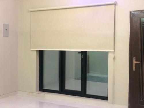 a window with a shade in a room at Home X4 in Al Wāşil