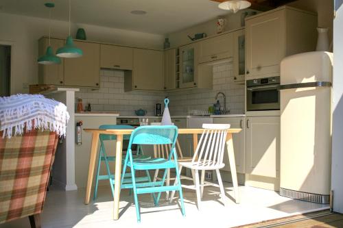 cocina con sillas, mesa y nevera en Owlers Retreat, en Camber