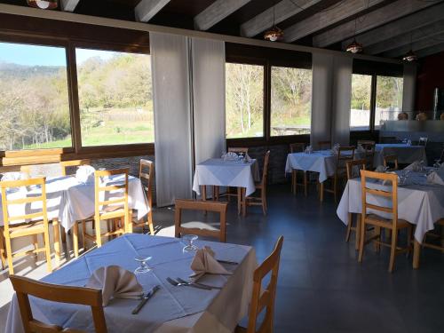 um restaurante com mesas e cadeiras brancas e janelas em Palia's Hotel em Laino Borgo