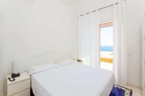 a white bedroom with a view of the ocean at Residence Due Torri in Maiori