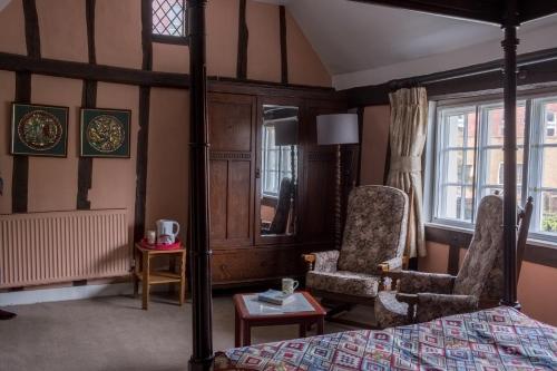 um quarto com uma cama, uma cadeira e janelas em St Mary’s Bed & Breakfast em Bury Saint Edmunds