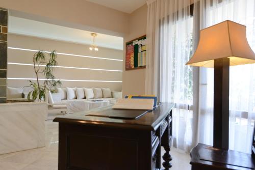 a room with a desk with a lamp and a couch at Eva Mare Hotel & Suites - Adults only in Agia Pelagia