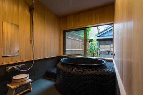 a bathroom with a large tub and a window at Sofuan in Kanazawa