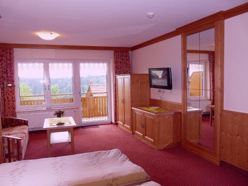 una habitación de hotel con una cama y un balcón en Gasthof Buglhof, en Sankt Englmar