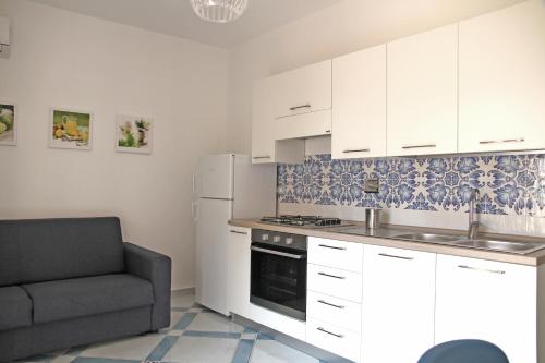 una cocina con armarios blancos y un sofá en una habitación en Corinto, en Canneto