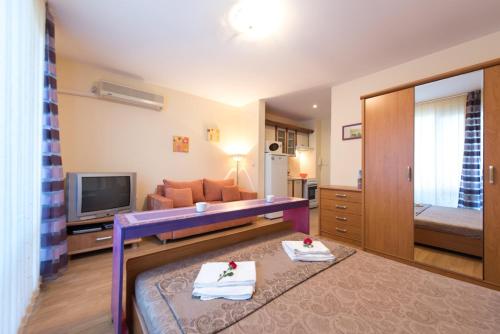 a living room with a purple couch and a television at GT Privilege Fort Beach Apartments in Elenite