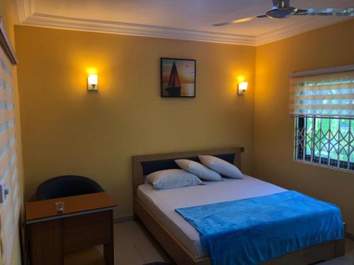 a bedroom with a bed and a desk and a window at Bonsukoda Lodge in Accra