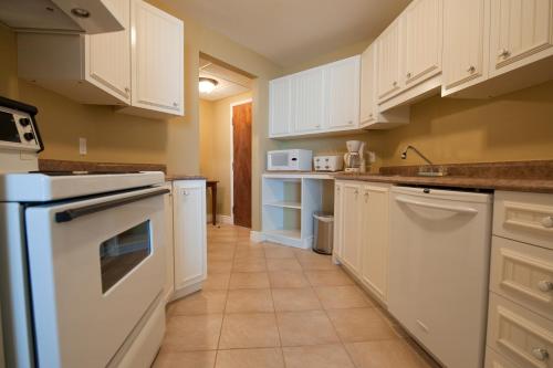 a kitchen with white cabinets and white appliances at Hôtel l'Empress in Rimouski