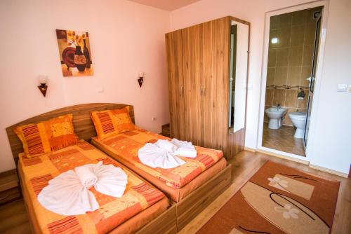 two beds in a small room with a bathroom at Vien Guest House in Bansko