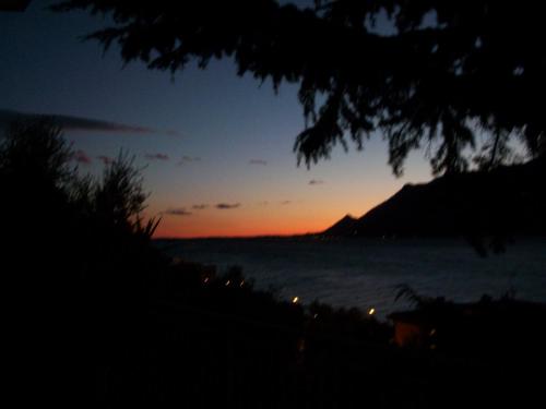 a sunset over the ocean with a mountain in the background at Hotel Casa Marinella in Malcesine